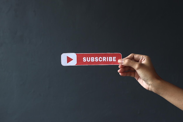 Photo hand holding printed paper with subscribe text and icon. vlogger asking online audience to subscribe