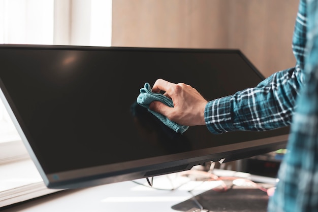 A hand holding a rag and wipe a digital monitor screen of device