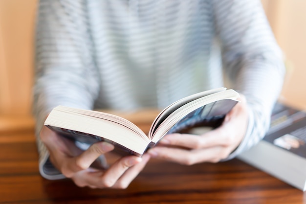 Foto mano che tiene e legge un libro a casa