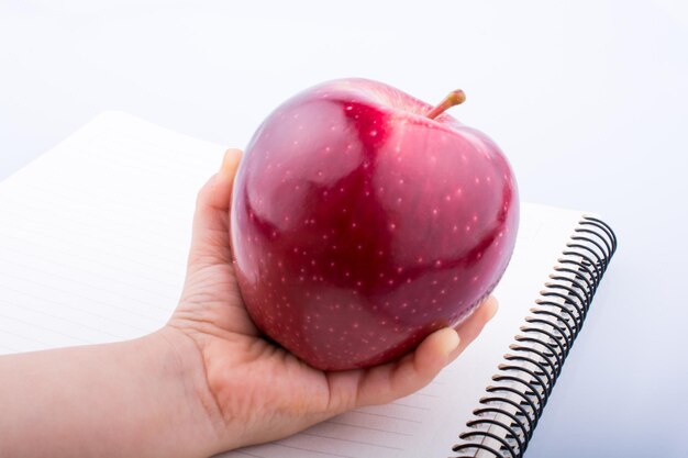 Hand holding a red apple on a notebook