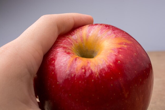 Hand holding a red apple on wood