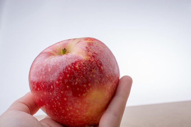 Hand holding a red apple on wood