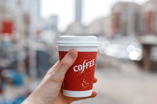 Hand holding a red cup of coffee