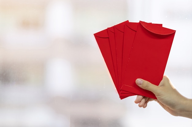 Hand holding red envelope or Ang pao. Chinese Lunar New Year celebrations concept