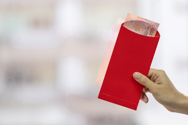 Photo hand holding red envelope or ang pao. chinese lunar new year celebrations concept