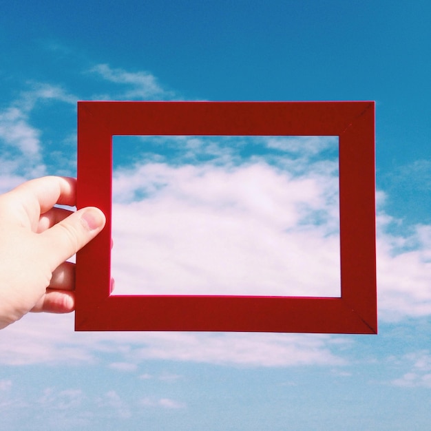 空に向かって赤いフレームを握る手