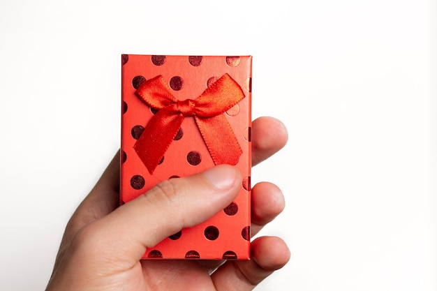 Hand holding red gift box with white background.