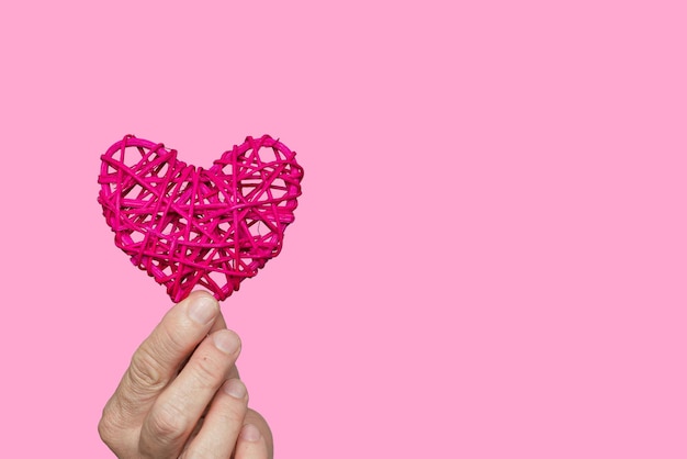 A hand holding a red heart shape rattan.