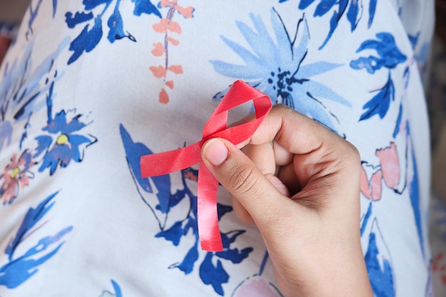 Hand holding red HIV ribbon top down
