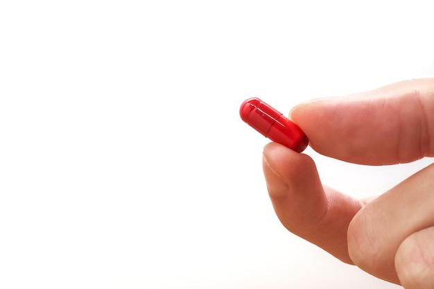 Hand holding a red medicine pill