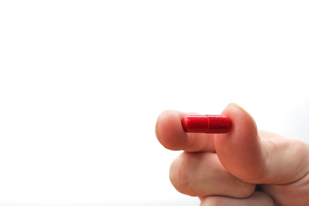 Hand holding a red medicine pill