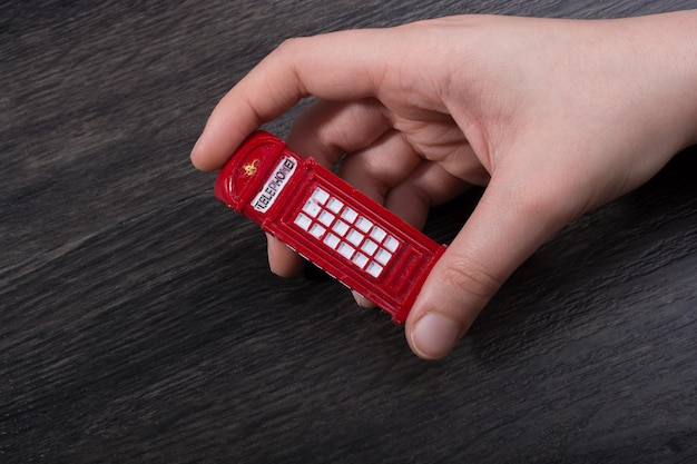 Hand holding a red phone booth