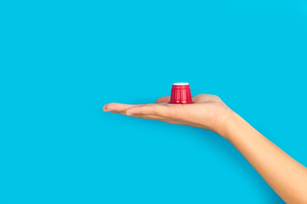 A hand holding a red plastic cup on a blue background