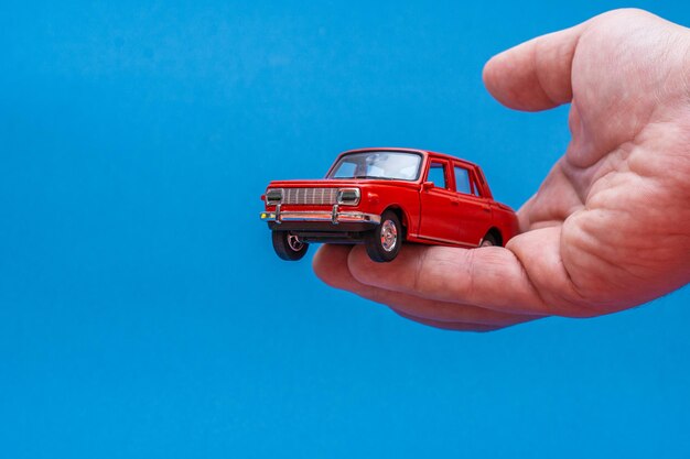 Hand holding red toy car isolated on blue background