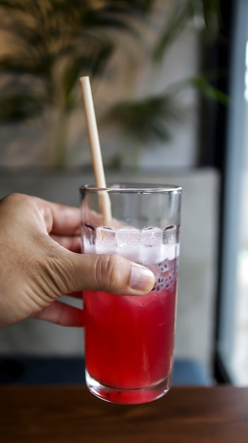 A hand holding a red watermelon juice at the cafe