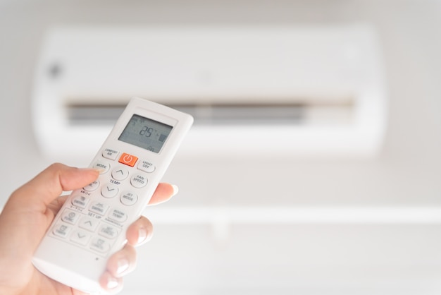 Hand holding remote controller directed on the air conditioner