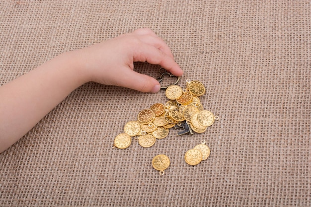 Hand holding a retro styled key over fake gold coins