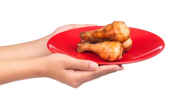 hand holding Roasted chicken leg on a dish isolated on white background