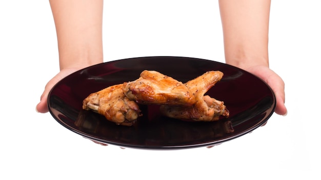 hand holding Roasted chicken wing on black dish isolated on white background