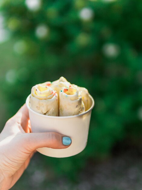 Hand holding rolled ice cream in cone cup