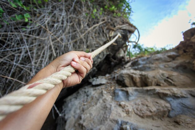 Hand holding rope at the hill