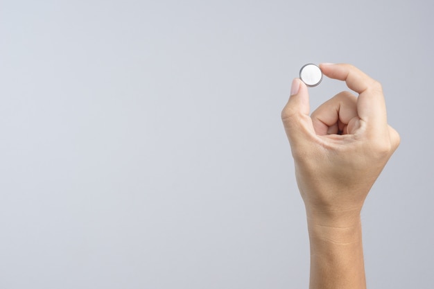 Hand holding round lithium button cell battery