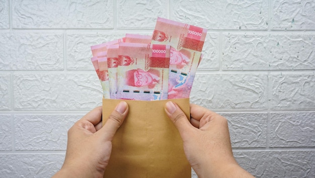 Hand holding rupiah Indonesian money on brown envelope