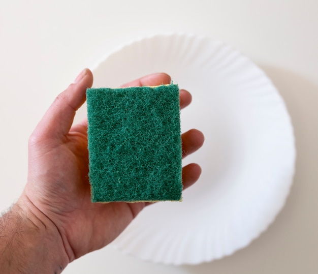 Hand holding scouring pad or sponge with white background plate