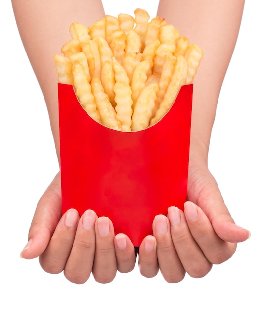 흰색 배경에 격리된 빨간색 종이 가방에 톱니 모양의 감자튀김을 들고 있는 손