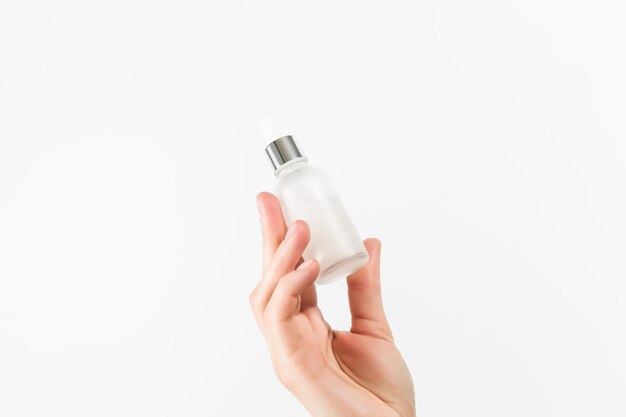 hand holding serum in a glass bottle on a white background skin care concept