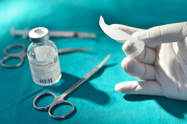 Рука с силиконовым носовым имплантатом в операционной с хирургическим оборудованием