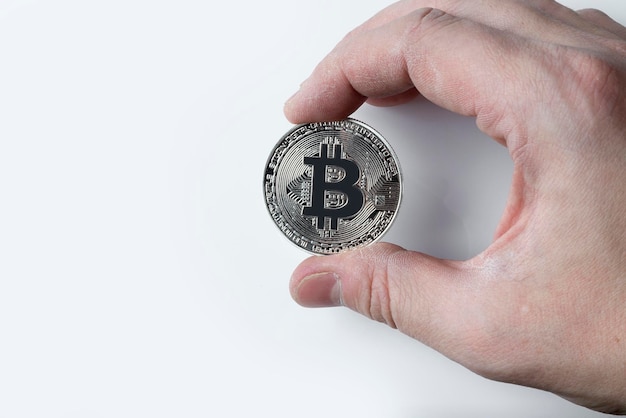 Hand holding a silver bitcoin on a white background