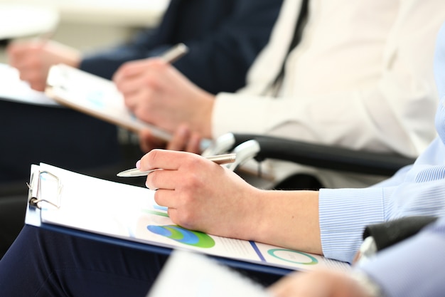 Hand holding silver pen and clipboard pad with statistics document