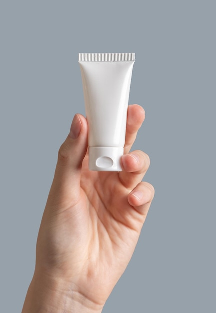 Hand holding small cream tube mock up blank white package for little cosmetic product