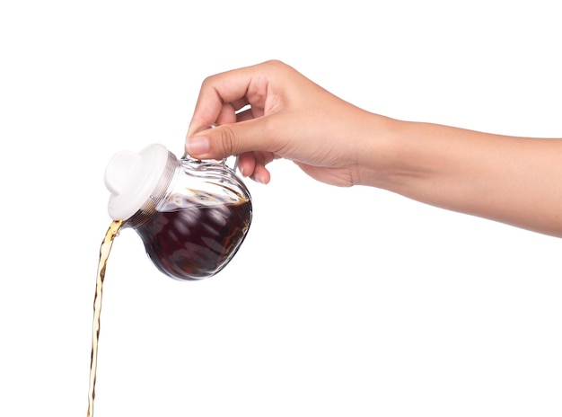 Photo hand holding small decanter with soy sauce isolated on the white background