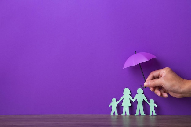 Hand holding a small purple umbrella insurance concept
