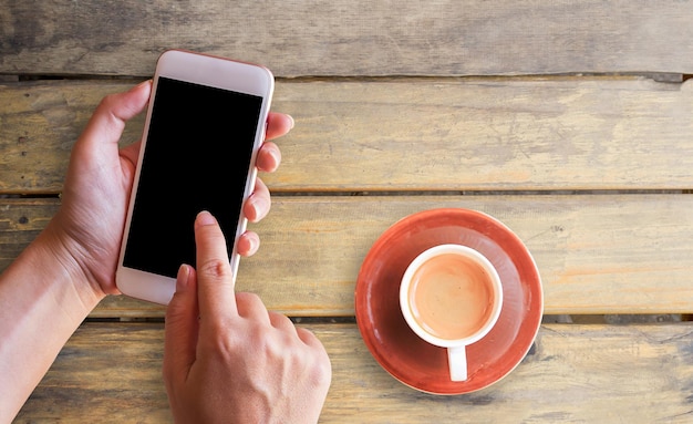 Hand holding smart phone and cup of coffee