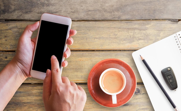 Hand holding smart phone and cup of coffee