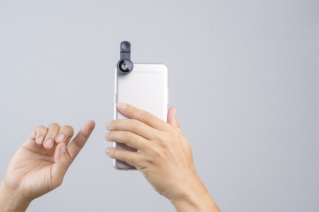 Hand holding smart phone equipped with extension lens