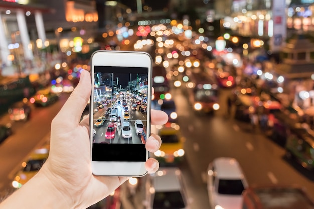 hand holding smart phone take pictures of traffic jam transportation at night by digital camera.