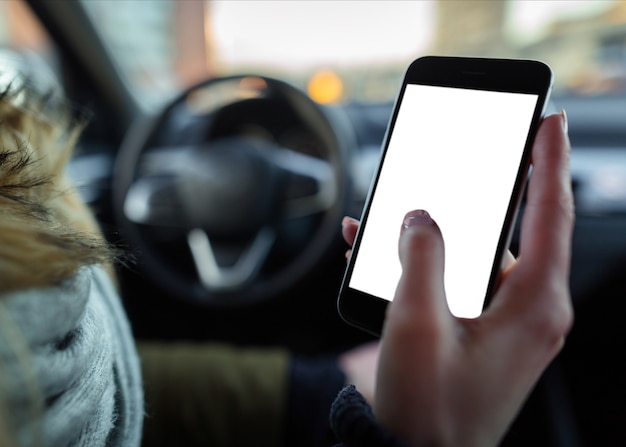 Hand holding a smart phone with blank screen in the car.