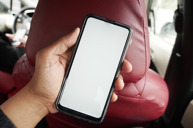 Hand holding smart phone with empty screen in a car