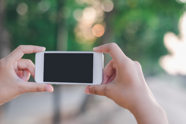 Hand holding smartphone on abstract bokeh background