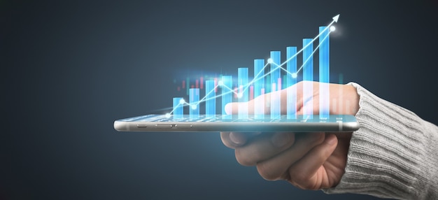 Hand holding smartphone device and touching screen. Stock exchange market concept. Trader looking on with graphs analysis candle