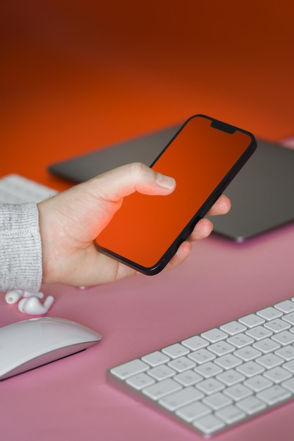 Photo hand holding a smartphone empty screeen office electronic devices in table