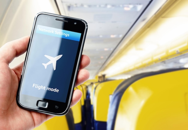 Mano che tiene smartphone all'interno dell'aereo