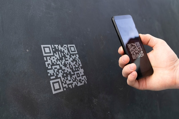 A hand holding a smartphone and scan the qr code to make a\
payment