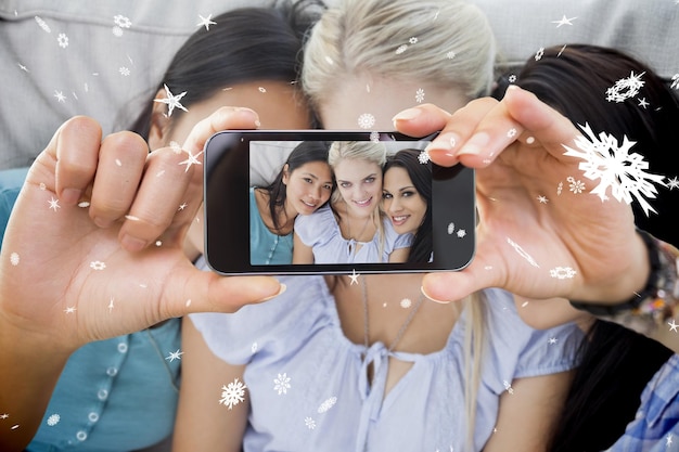 Hand holding smartphone showing close friends smiling at camera