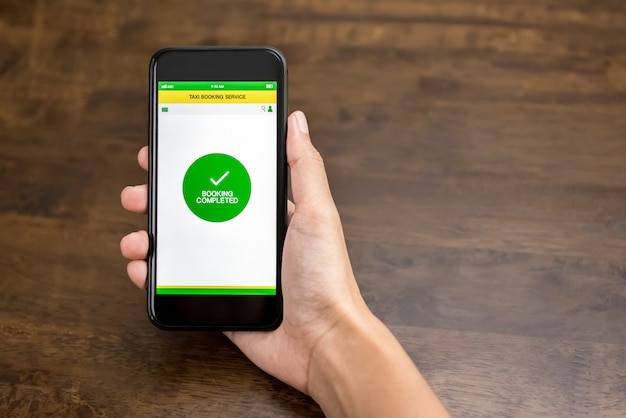 택시 예약 응용 프로그램에서 확인 텍스트를 보여주는 손 잡고 스마트 폰