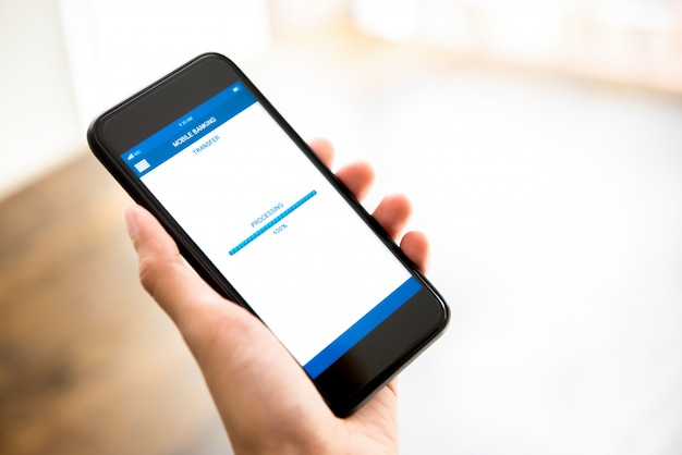 Hand holding smartphone showing processing of money transferring online via application